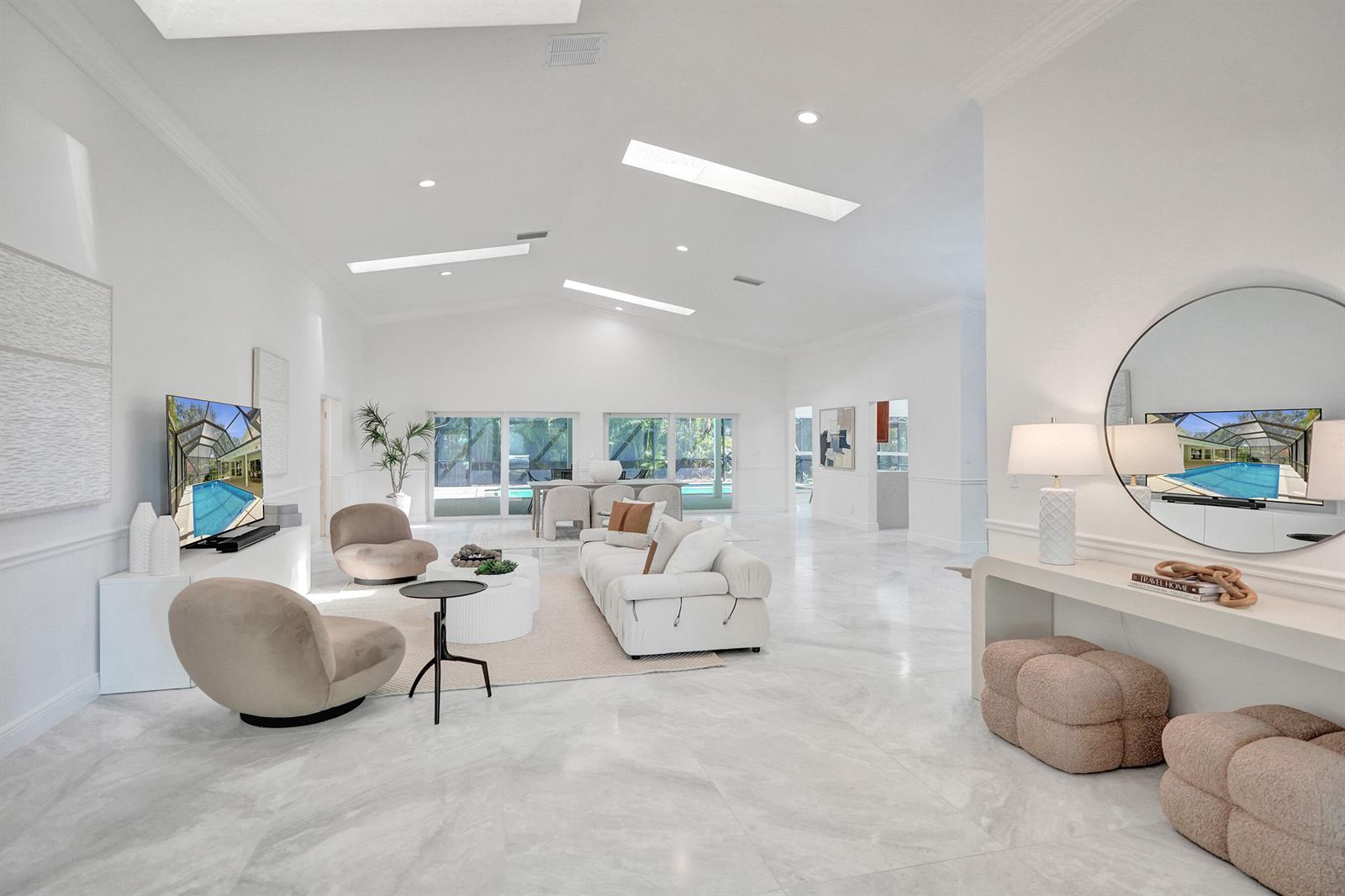 A bright, open-concept living room features white walls, marble flooring, skylights, and modern furniture — 2401 NW 39th Street, Boca Raton FL 33431, BOCA RATON, FL