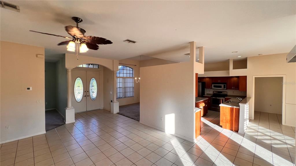 An open-concept living area features tile flooring, a ceiling fan, and a kitchen with wood cabinets — 9140 LAMBORN STREET, SPRING HILL, FL
