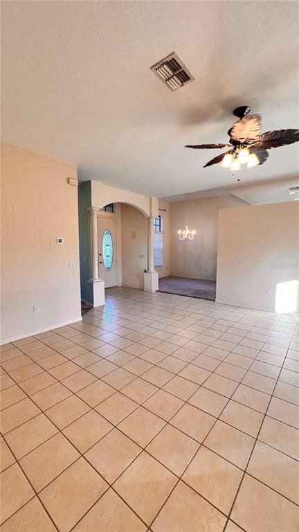 An open-concept living area features light-colored tile flooring, an arched entryway, and a ceiling fan — 9140 LAMBORN STREET, SPRING HILL, FL