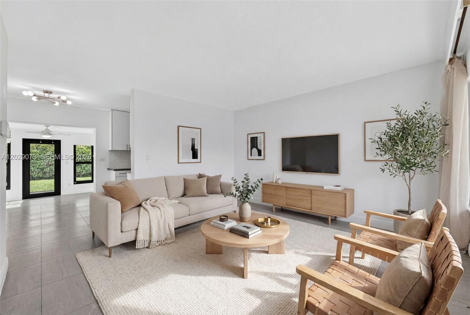 A bright living room features a beige sofa, two wooden chairs, and a round coffee table — 680 W 50th Pl, Hialeah FL 33012, HIALEAH, FL