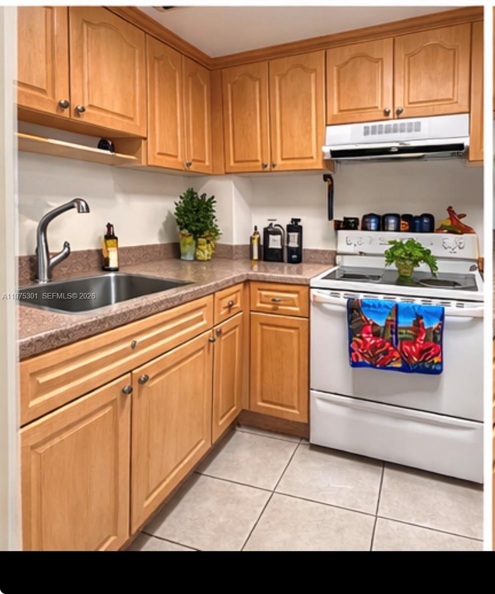 A kitchen features light wood cabinets, a brown speckled countertop, a white stove, and tile flooring — 3301 NE 5th Ave # 519, Miami FL 33137, MIAMI, FL