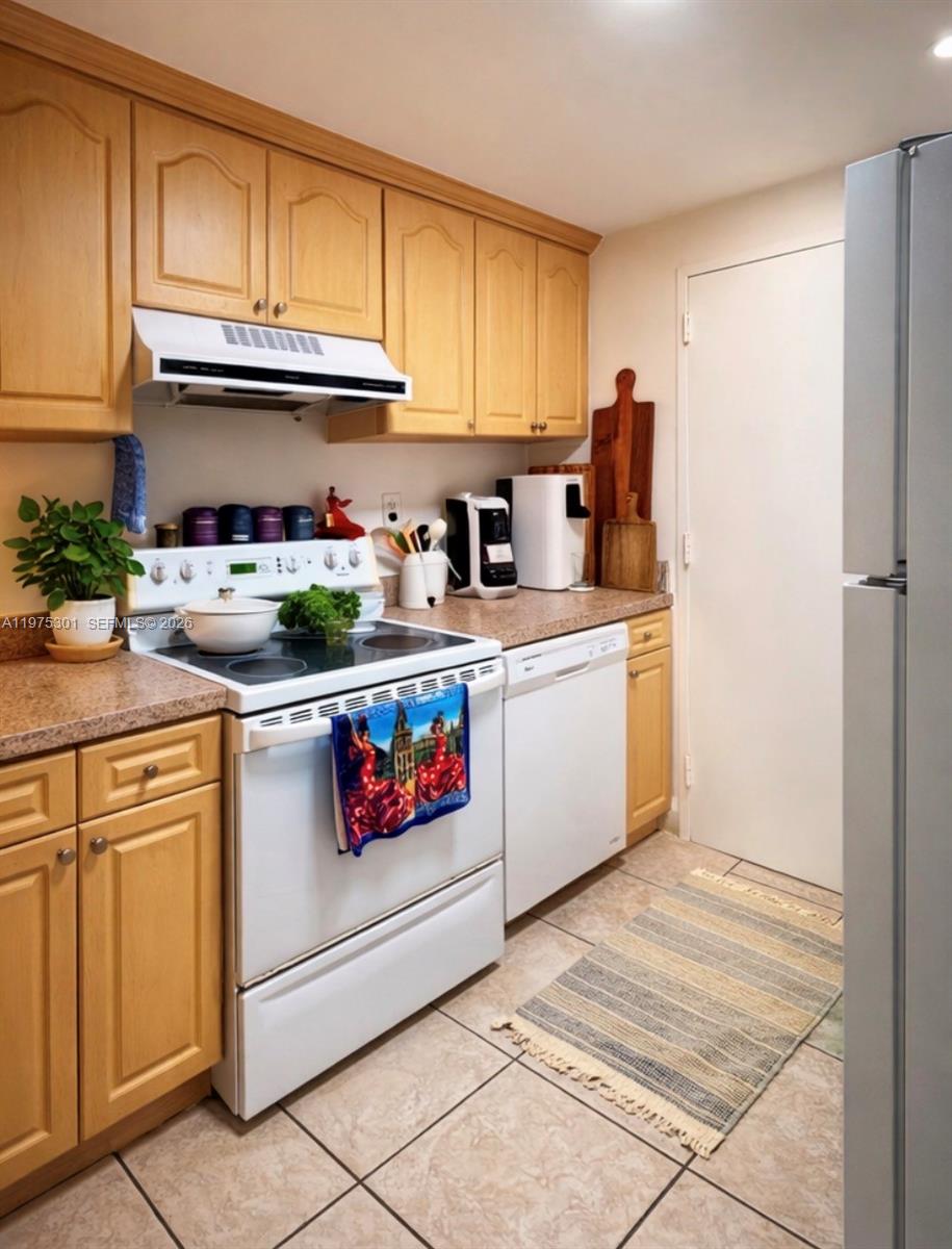 A kitchen features light wood cabinets, white appliances, and a tiled floor — 3301 NE 5th Ave # 519, Miami FL 33137, MIAMI, FL