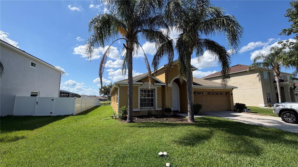 A single-story house with a tan exterior, a two-car garage, and two palm trees — 31205 BRIDGEGATE DRIVE, WESLEY CHAPEL, FL