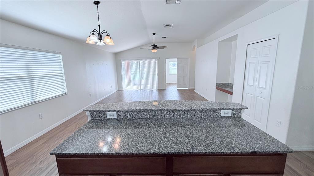 A kitchen island with a granite countertop overlooks a living area with wood-look flooring — 31205 BRIDGEGATE DRIVE, WESLEY CHAPEL, FL