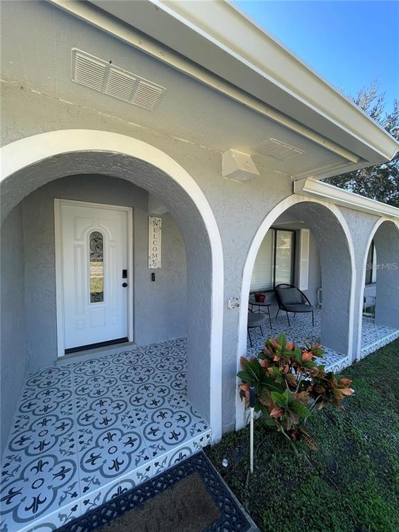 A gray stucco house exterior features arched entryways and a patterned tile porch floor — 3140 TCU BOULEVARD, ORLANDO, FL