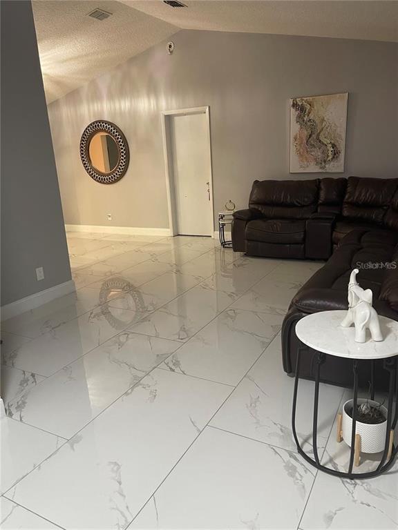 A living room features large white marble-look floor tiles, a dark leather sectional, and a mirror — 3140 TCU BOULEVARD, ORLANDO, FL