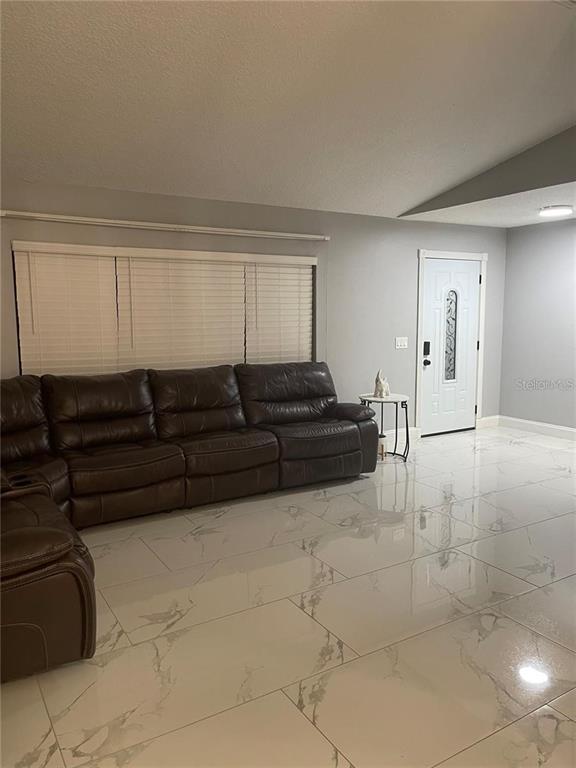 A living room features a large brown sectional sofa, white tile flooring, and a front door — 3140 TCU BOULEVARD, ORLANDO, FL
