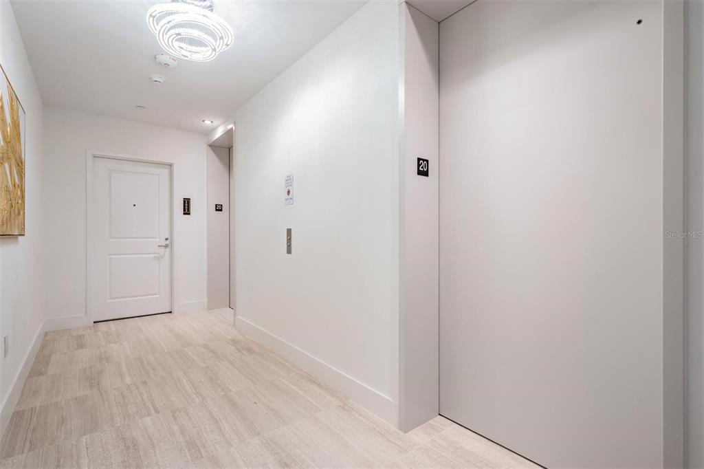 A hallway features light wood-look flooring, a white door, and a large elevator door — 3015 S YSABELLA AVENUE UNIT 2003, TAMPA, FL