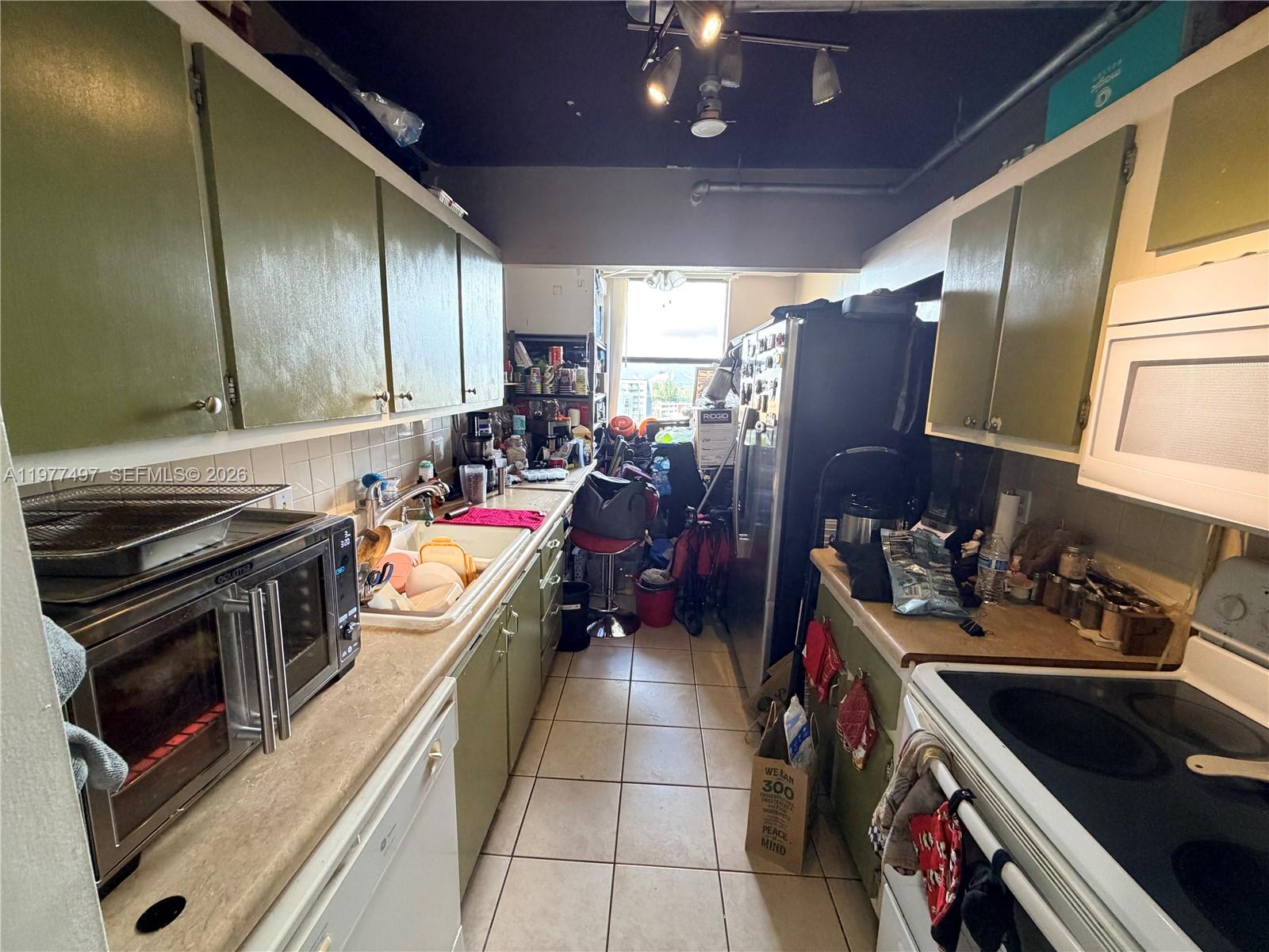 A narrow galley kitchen features green cabinets, a stainless steel toaster oven, and tiled floors — 1470 NE 123rd St # A1116, North Miami FL 33161, NORTH MIAMI, FL