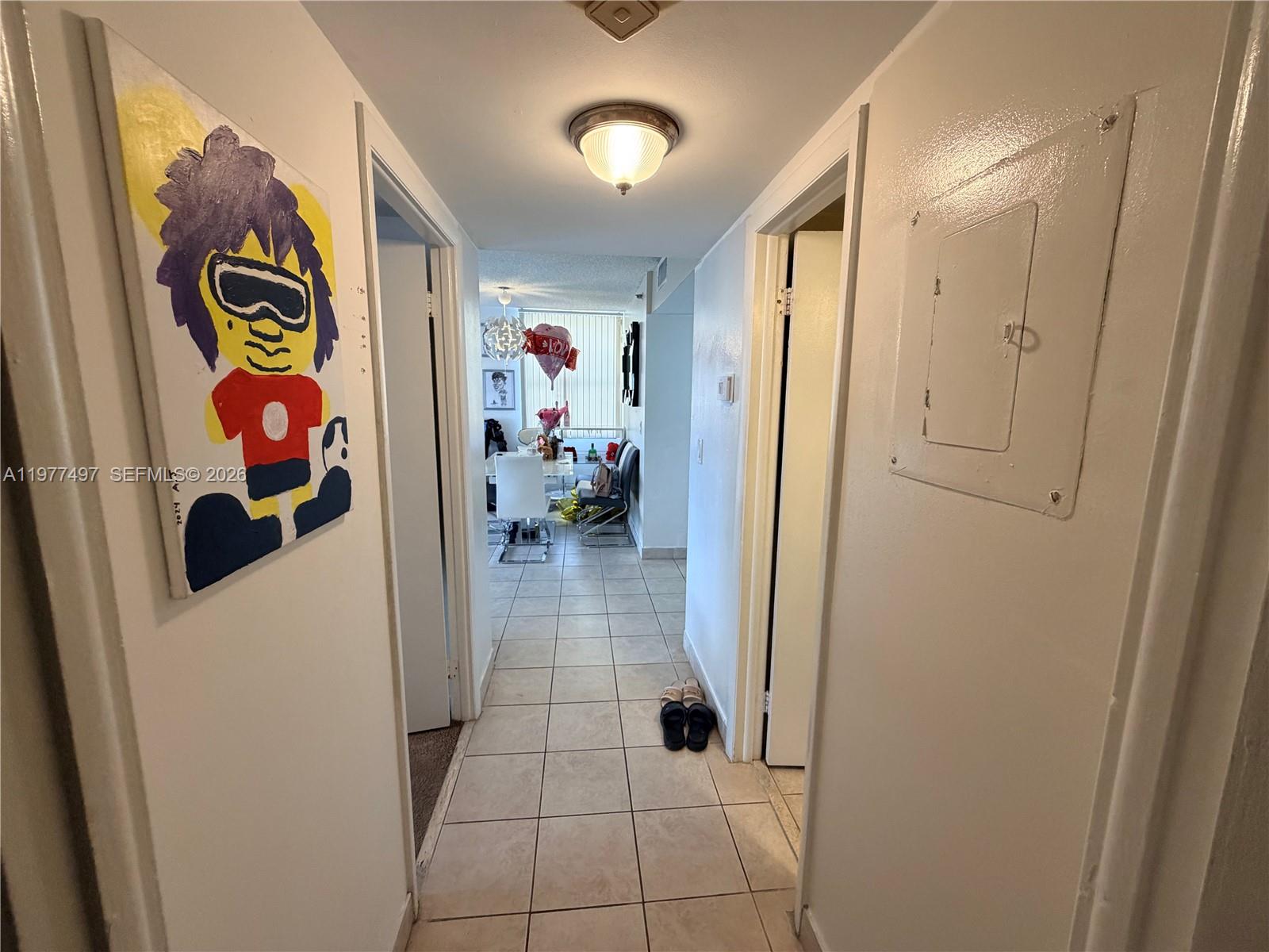 A tiled hallway leads to a dining area featuring a painting on the left wall — 1470 NE 123rd St # A1116, North Miami FL 33161, NORTH MIAMI, FL