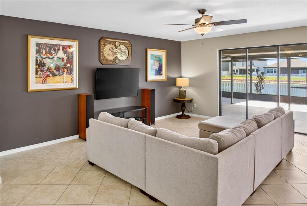 A living room features a large sectional sofa, a wall-mounted television, and sliding glass doors — 13415 WHITE SAPPHIRE ROAD, RIVERVIEW, FL