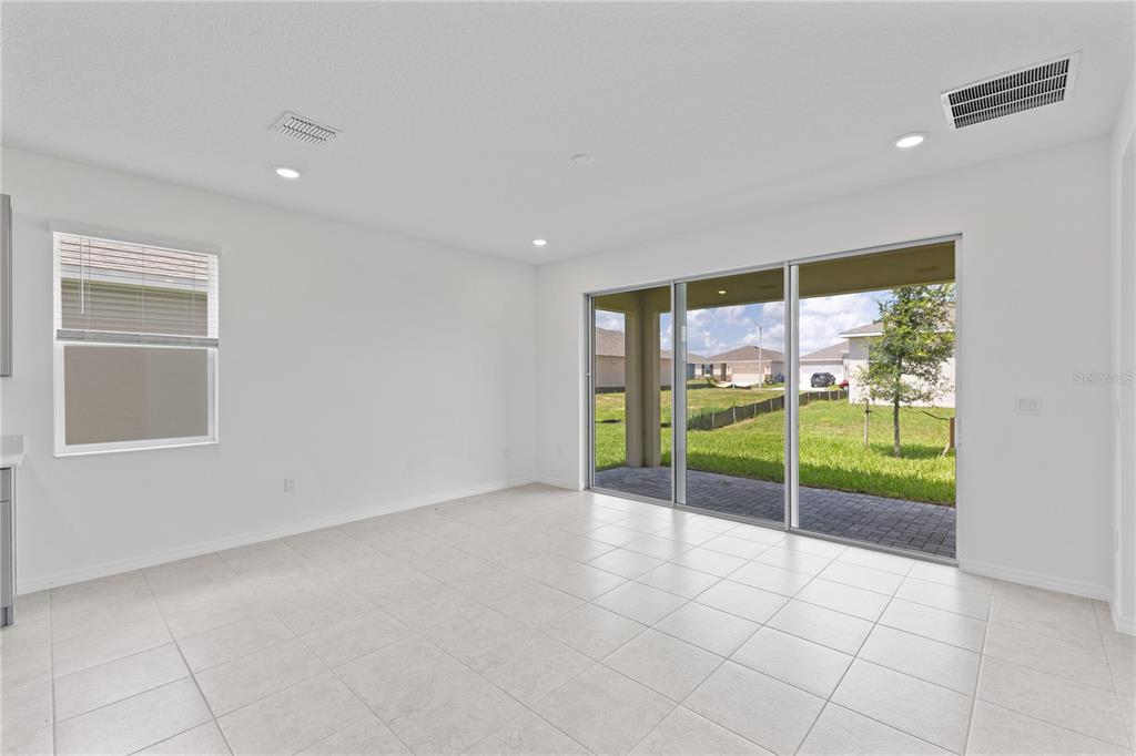 An empty room with white walls, tile flooring, and a large sliding glass door — 491 SILVER PALM DRIVE, HAINES CITY, FL