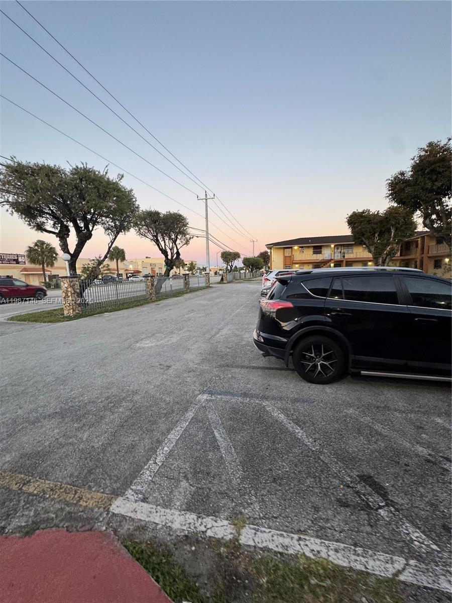 A black SUV is parked in an asphalt lot next to a multi-story apartment building — 4050 NW 135th St # 1, Opa-Locka FL 33054, OPA-LOCKA, FL
