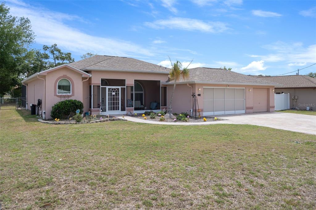 A single-story peach-colored house with a screened front porch and a two-car garage — 4312 BAYRIDGE COURT, SPRING HILL, FL