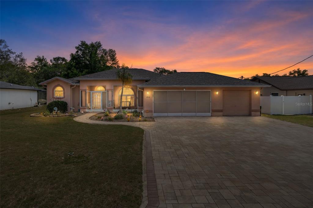A single-story house with a paved driveway, a two-car garage, and a sunset sky — 4312 BAYRIDGE COURT, SPRING HILL, FL