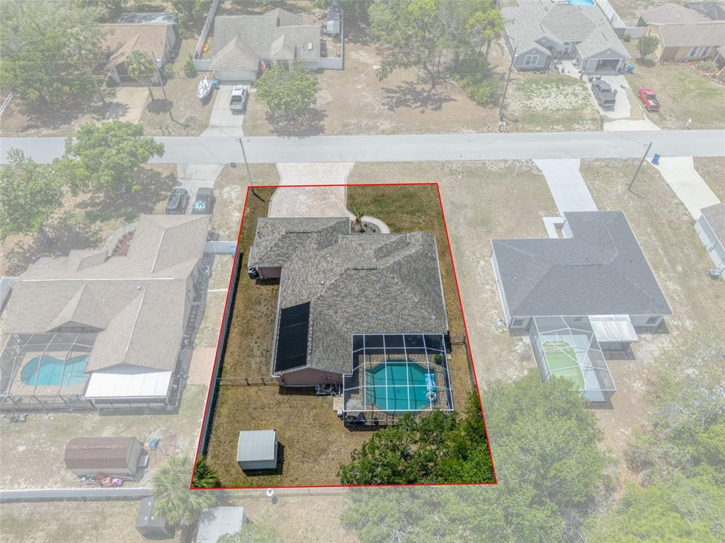 An aerial view shows a house with a pool enclosure, solar panels, and a shed — 4312 BAYRIDGE COURT, SPRING HILL, FL