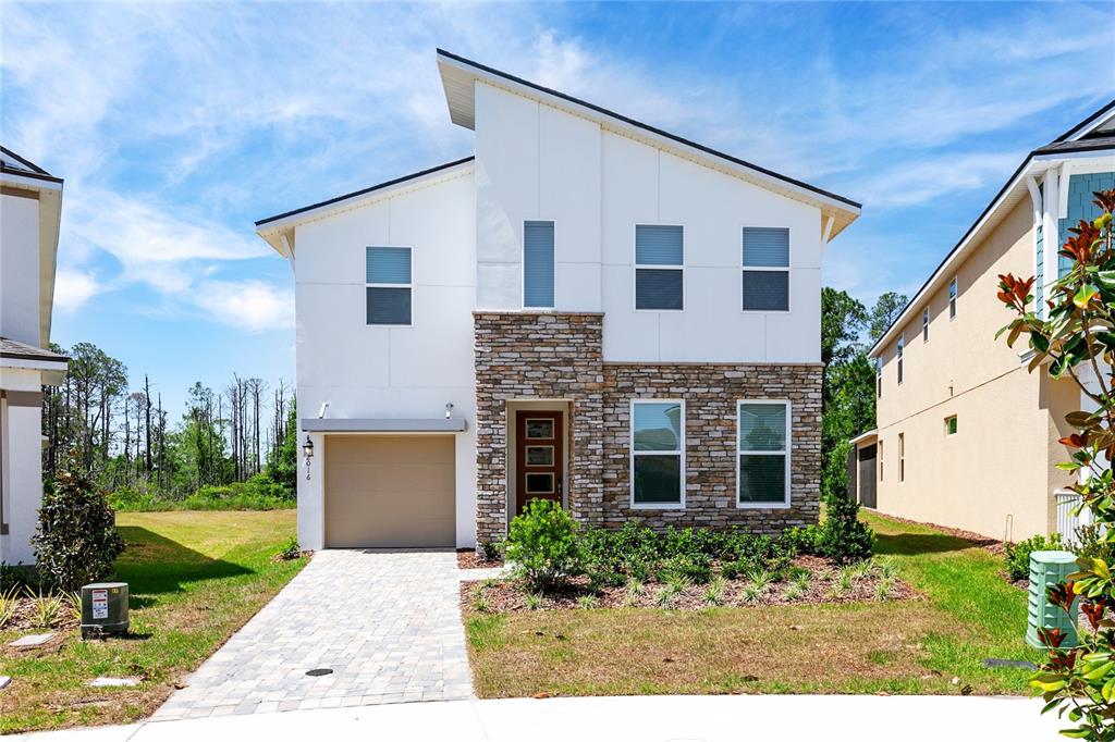 A two-story house with a stone facade, white siding, and a single-car garage — 2016 FLEMING MIST PLACE, KISSIMMEE, FL