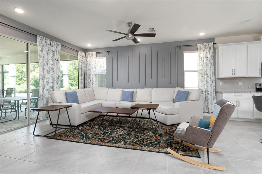 A living room features a white sectional sofa, a patterned rug, and a gray accent wall — 2016 FLEMING MIST PLACE, KISSIMMEE, FL