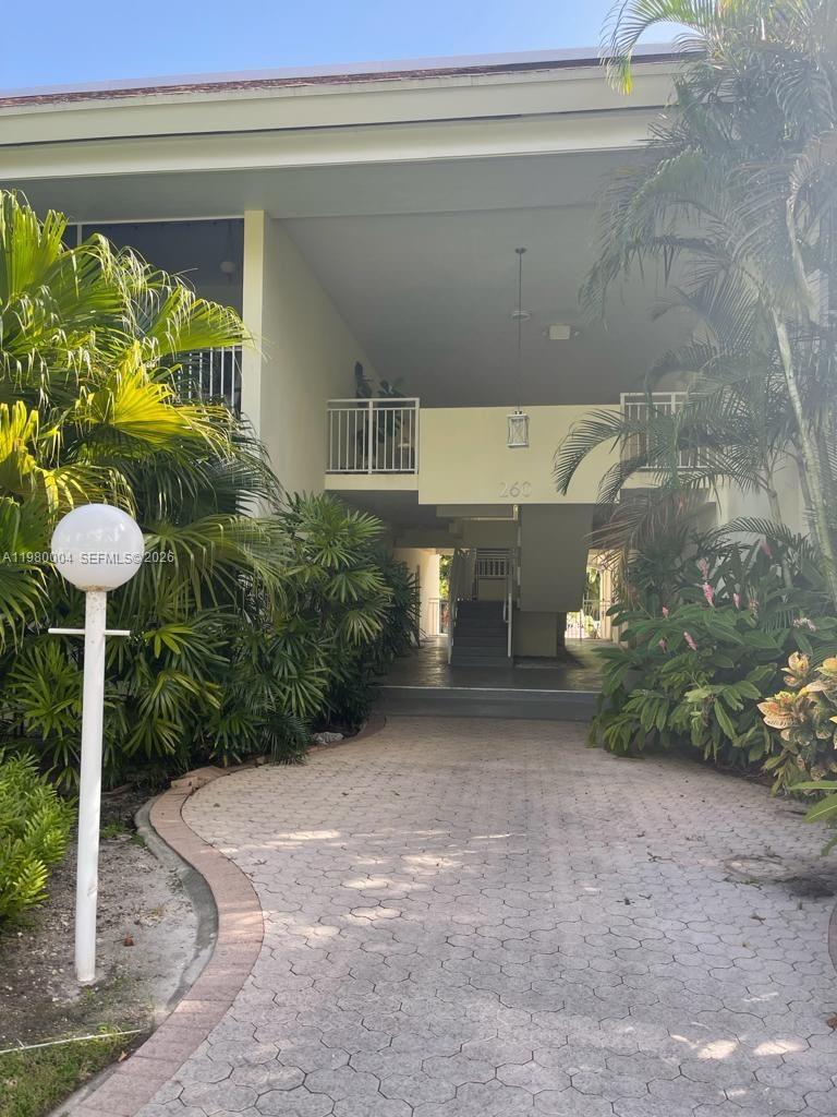 A paved walkway leads to the entrance of a two-story building with lush landscaping — 260 Sunrise Dr # H, Key Biscayne FL 33149, KEY BISCAYNE, FL