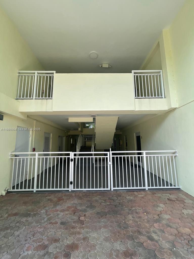A white metal gate secures the entrance to a covered outdoor walkway between apartment buildings — 260 Sunrise Dr # H, Key Biscayne FL 33149, KEY BISCAYNE, FL