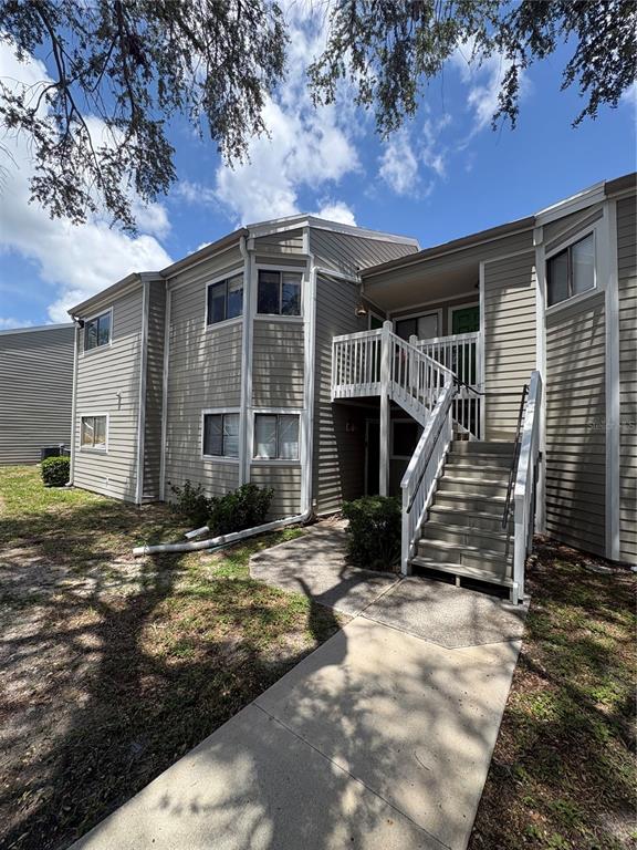 A two-story apartment building with light-colored siding, a concrete walkway, and an exterior staircase — 7298 ULMERTON ROAD UNIT 407, LARGO, FL