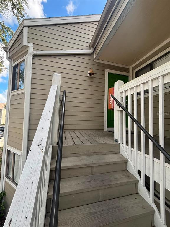 An exterior view of a wooden staircase leading to a green front door — 7298 ULMERTON ROAD UNIT 407, LARGO, FL