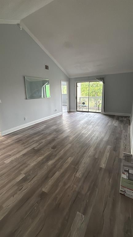 An empty living room features vaulted ceilings, light gray walls, and wood-look laminate flooring — 7298 ULMERTON ROAD UNIT 407, LARGO, FL