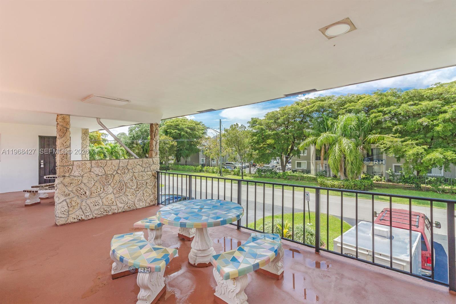A covered balcony features a stone wall, a tiled table with benches, and metal railings — 344 SW 1st St # 6, Pompano Beach FL 33060, POMPANO BEACH, FL