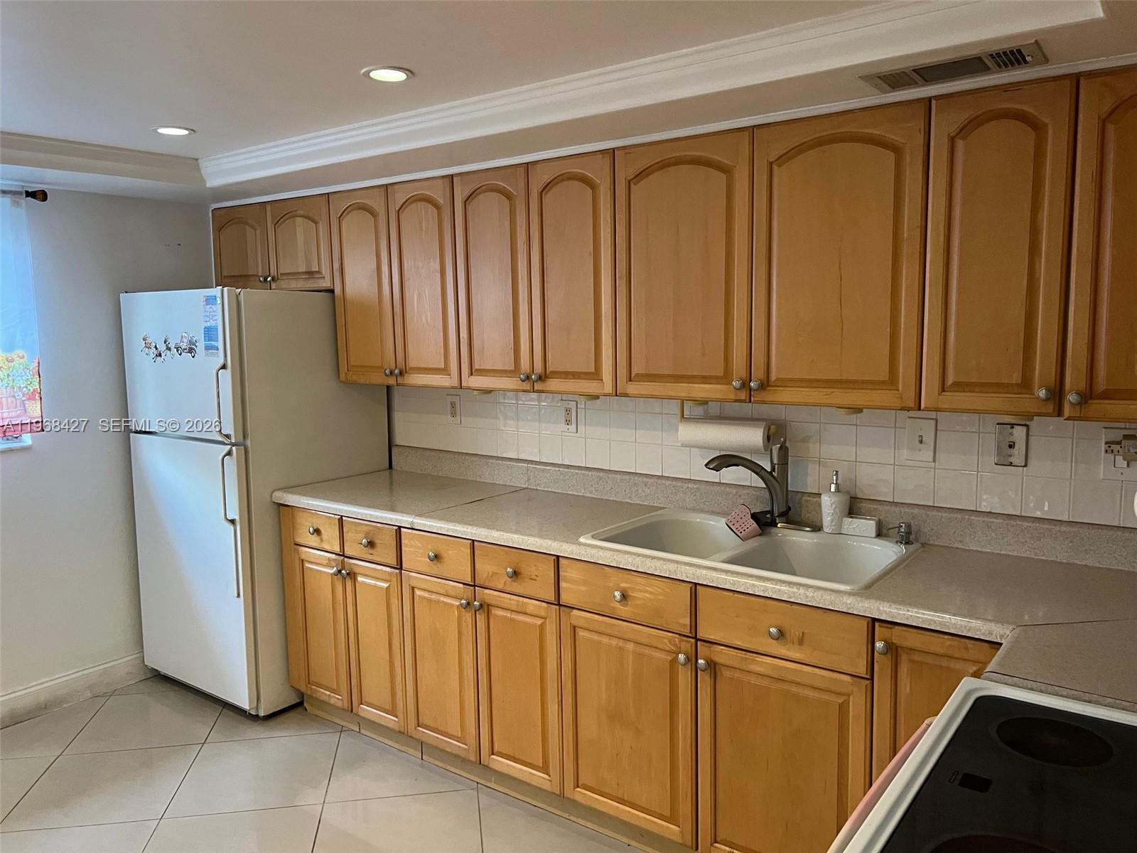 A kitchen features light wood cabinets, a white refrigerator, and a double-basin sink — 344 SW 1st St # 6, Pompano Beach FL 33060, POMPANO BEACH, FL