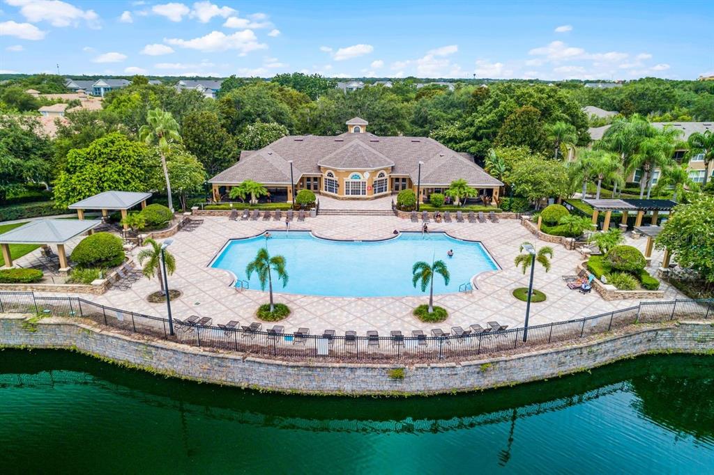 An aerial view of a community swimming pool and clubhouse situated next to a lake — 6349 MIRAMONTE DRIVE UNIT 101, ORLANDO, FL