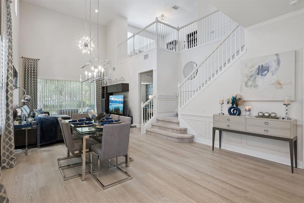 A dining area with a glass table and chairs sits beneath a high ceiling — 6349 MIRAMONTE DRIVE UNIT 101, ORLANDO, FL