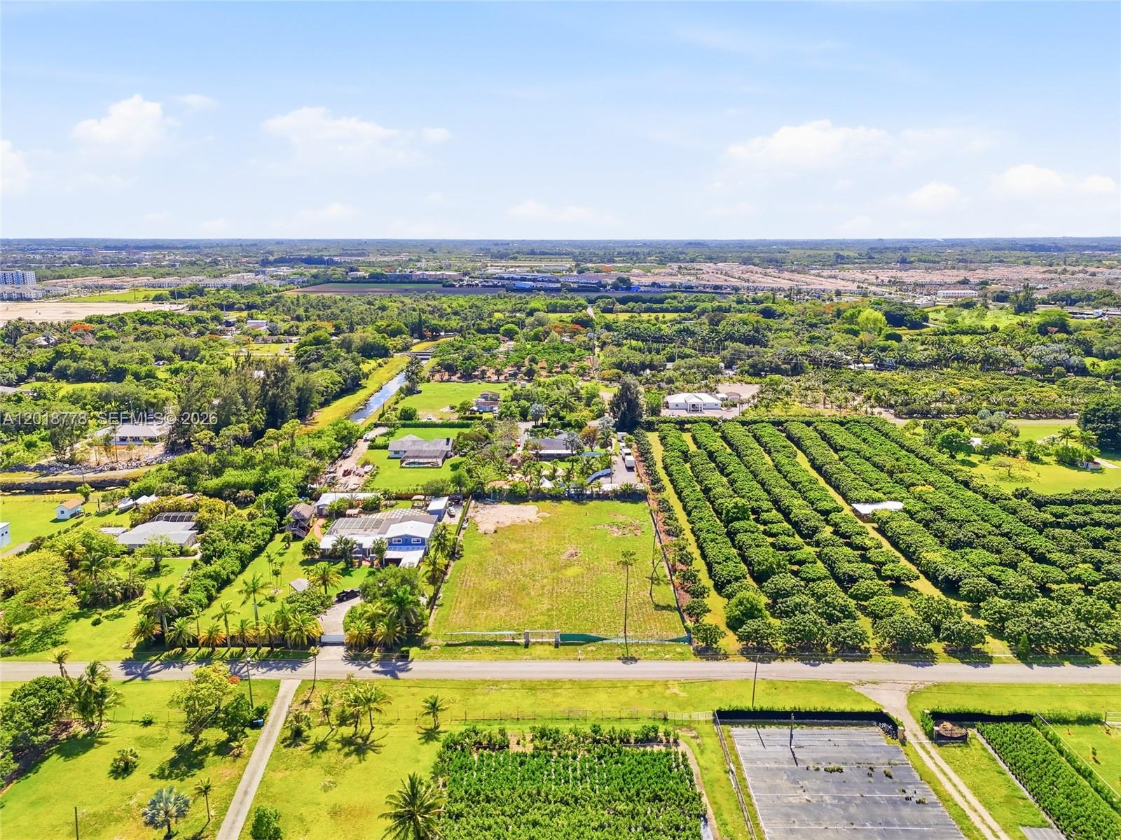 An aerial view shows a rural landscape with houses, open fields, and rows of trees — 23600 SW 122 AVE, Miami FL 33032, MIAMI, FL