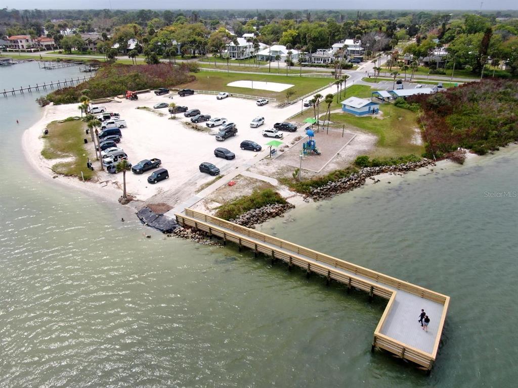 An aerial view shows a wooden pier extending into the water near a parking lot — 1508 SABAL PALM DR, EDGEWATER, FL
