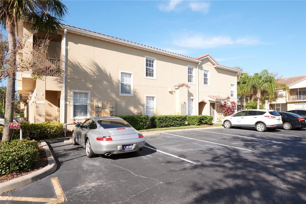 A two-story tan apartment building with a parking lot and a silver sports car — 7505 PELLHAM WAY, KISSIMMEE, FL