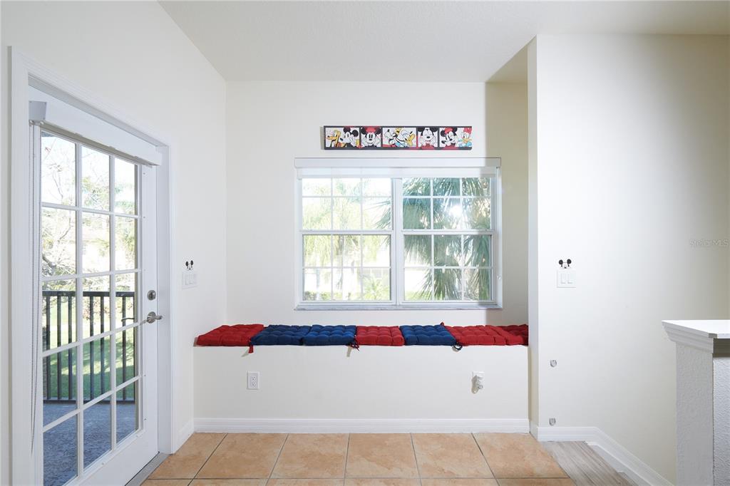 A room features a built-in window seat with red and blue cushions and tile flooring — 7505 PELLHAM WAY, KISSIMMEE, FL