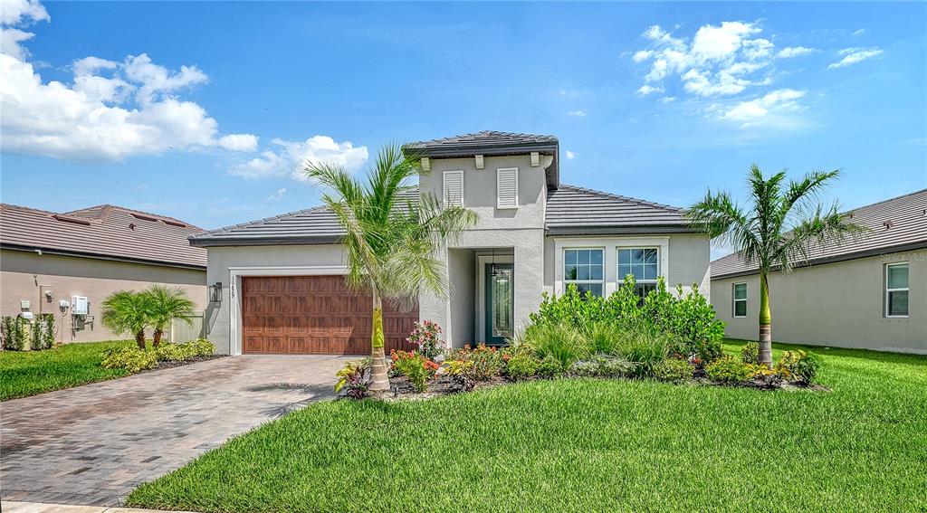 A single-story house with a paved driveway, palm trees, and a tiled roof — 11829 LILAC PEARL LANE, PARRISH, FL