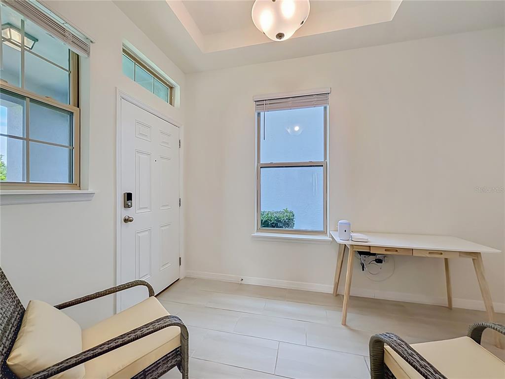 A bright entryway features white walls, tile flooring, a desk, and two wicker chairs — 11117 BOSTWICK ALLEY, WINTER GARDEN, FL