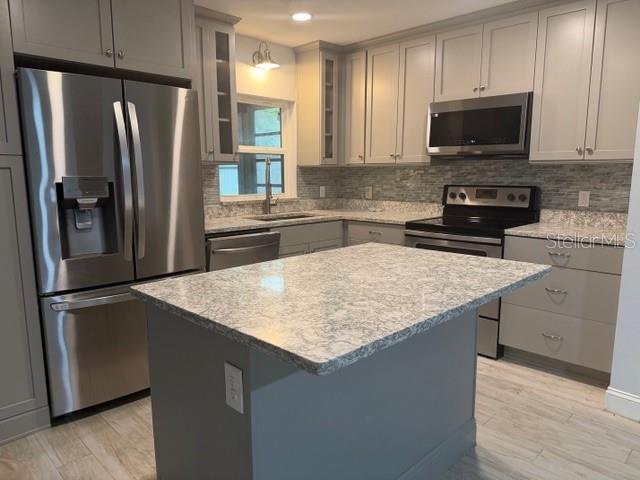 A kitchen features gray cabinets, stainless steel appliances, a granite island, and light tile flooring — 901 BALTIMORE DRIVE, ORLANDO, FL