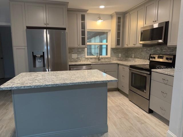 A kitchen features gray cabinets, stainless steel appliances, a kitchen island, and light-colored flooring — 901 BALTIMORE DRIVE, ORLANDO, FL