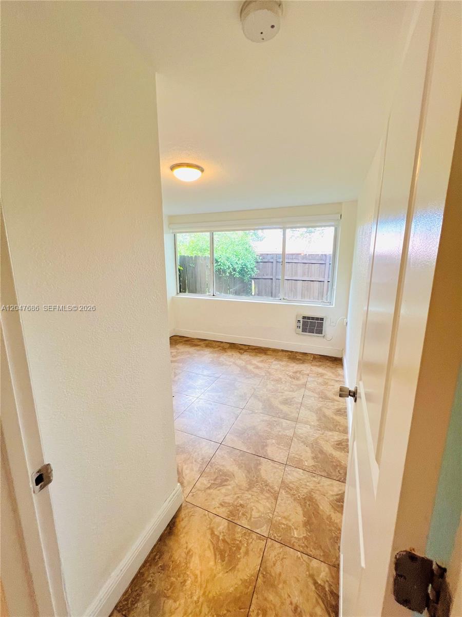 A small room with tiled floors, a large window, and a wall-mounted air conditioning unit — 410 Pinecrest Dr # 1, Miami Springs FL 33166, MIAMI SPRINGS, FL