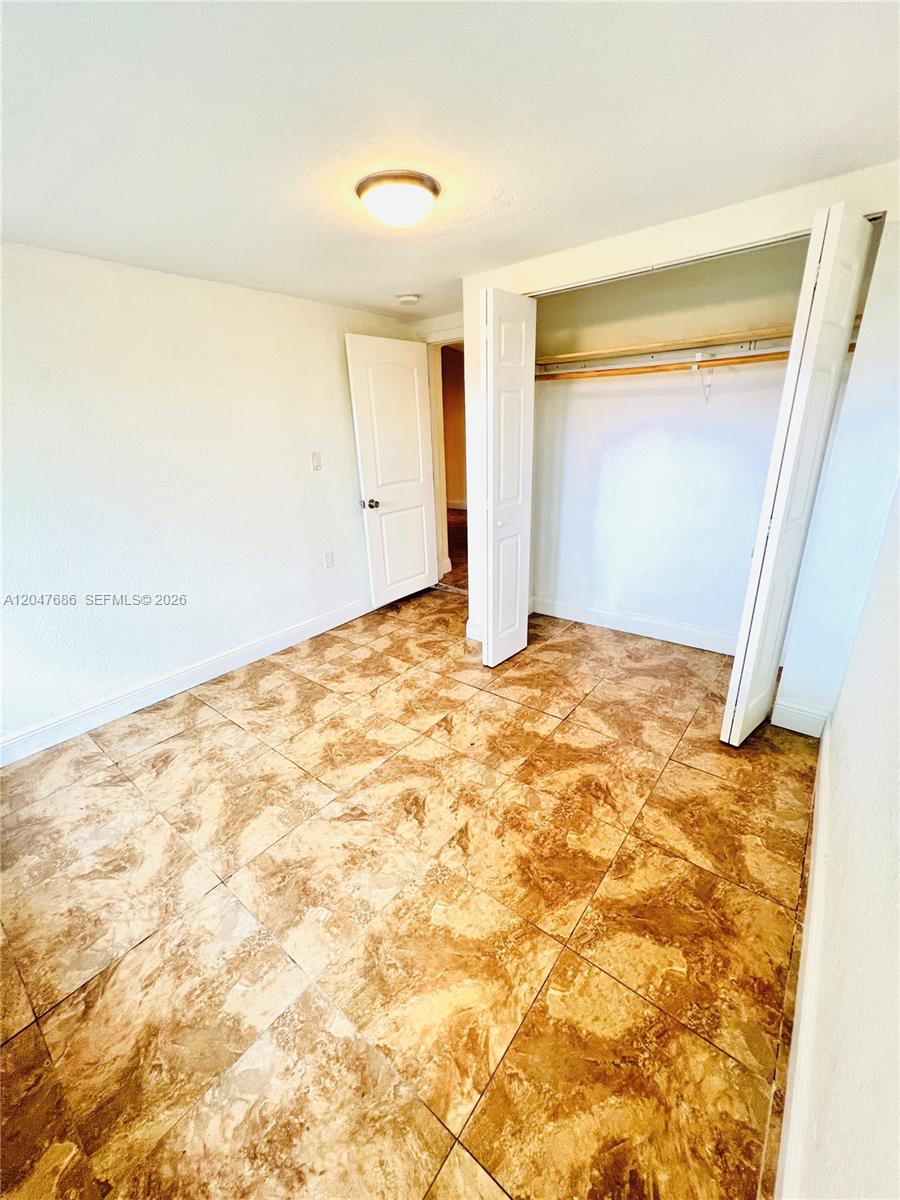 This room features beige tile flooring, a ceiling light, and an open closet — 410 Pinecrest Dr # 1, Miami Springs FL 33166, MIAMI SPRINGS, FL