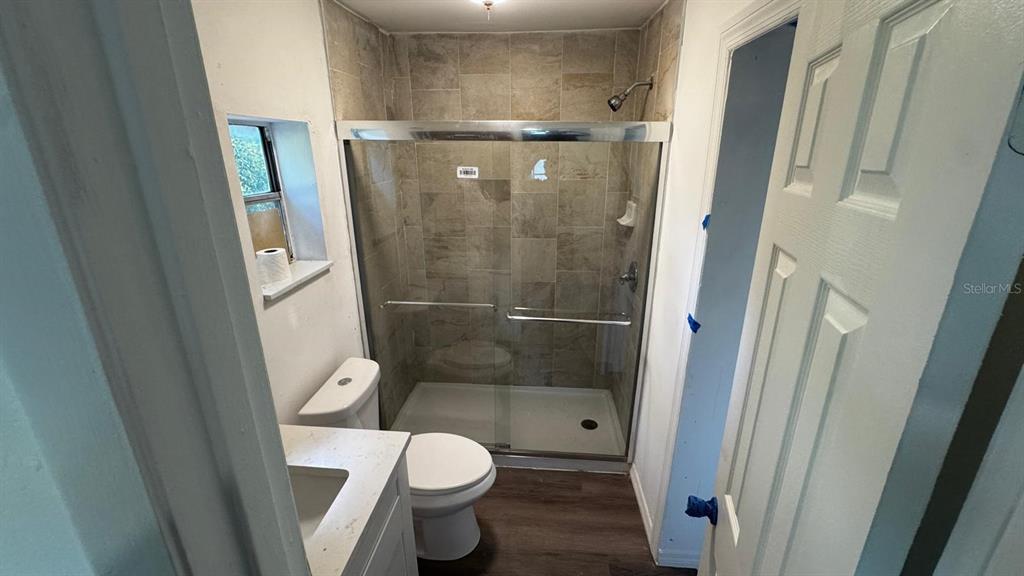 A bathroom features a tiled walk-in shower, a white vanity, and a toilet — 345 AVENUE P NE, WINTER HAVEN, FL