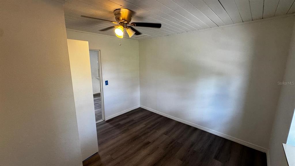 An empty room features white walls, a ceiling fan, and dark wood-look flooring — 345 AVENUE P NE, WINTER HAVEN, FL
