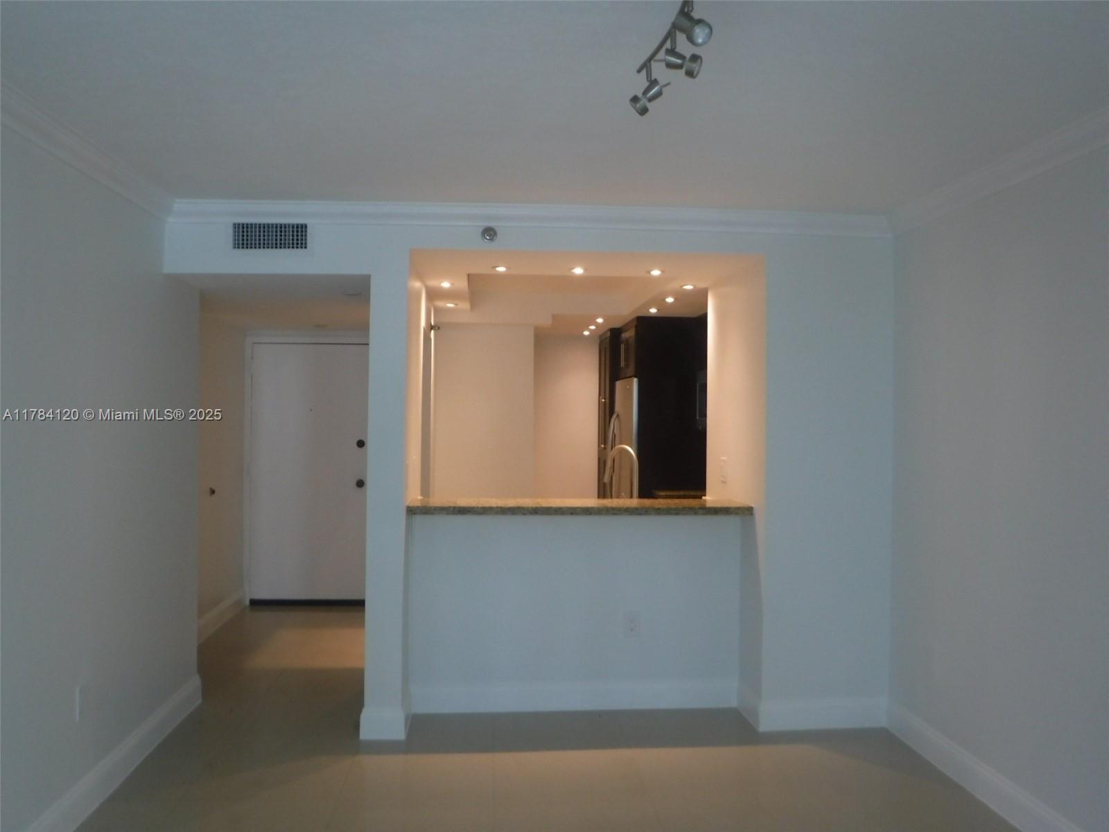 A kitchen with a breakfast bar opens into a living area with light-colored tile floors — 850 N Miami Ave # 2101, Miami FL 33136, MIAMI, FL