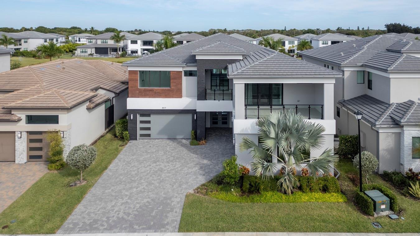 A modern two-story house features a paved driveway, two garage doors, and a balcony — 8571 Shoreacres Street, Boca Raton FL 33434, BOCA RATON, FL