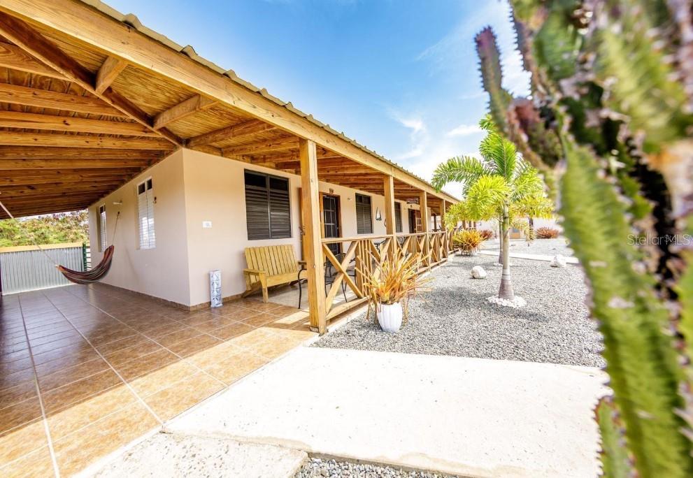 A covered patio with tile flooring and a wooden railing overlooks a gravel yard — B-13 CARR 3301 KM HM 1.9 INT STREET UNIT B-13, CABO ROJO, PR