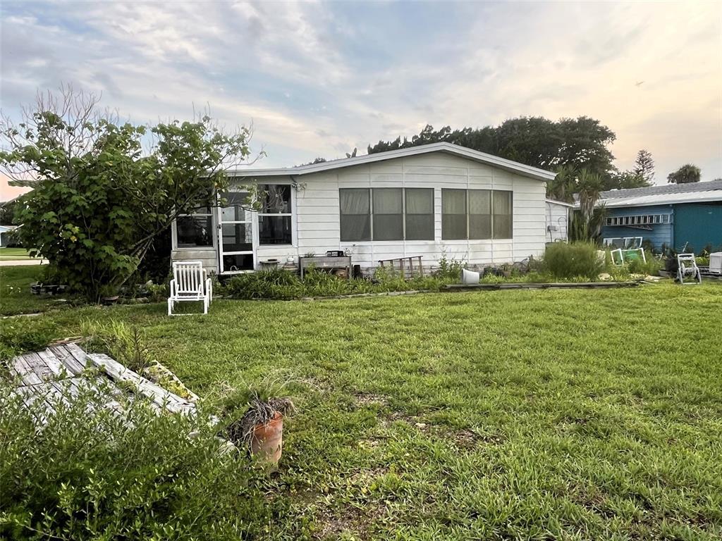 A white manufactured home sits on a grassy lot with a small patio area — 281 GOLDEN BAY BOULEVARD, OAK HILL, FL