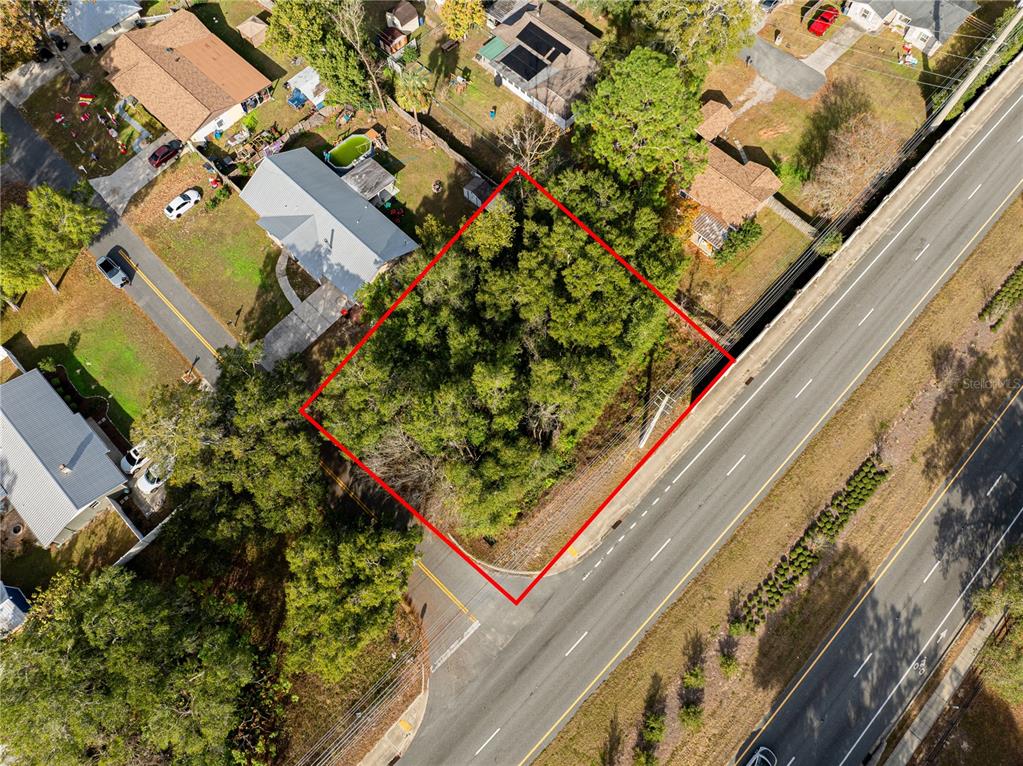 An aerial view shows a vacant, wooded lot outlined in red next to a road — SE 4TH STREET, OCALA, FL