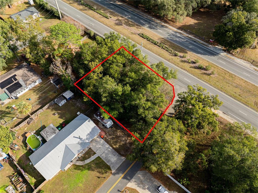 An aerial view shows a wooded, rectangular lot outlined in red next to a road — SE 4TH STREET, OCALA, FL