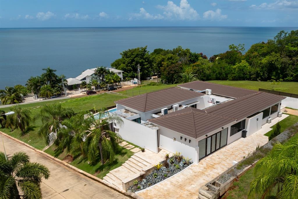 An aerial view shows a modern white house with a brown tiled roof near water — 6 PARAISO ESCONDIDO, CABO ROJO, PR